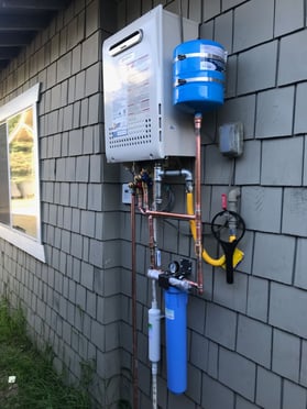 A tankless water heater on the side of a house