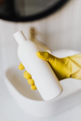 Gloved hand holding drain cleaner