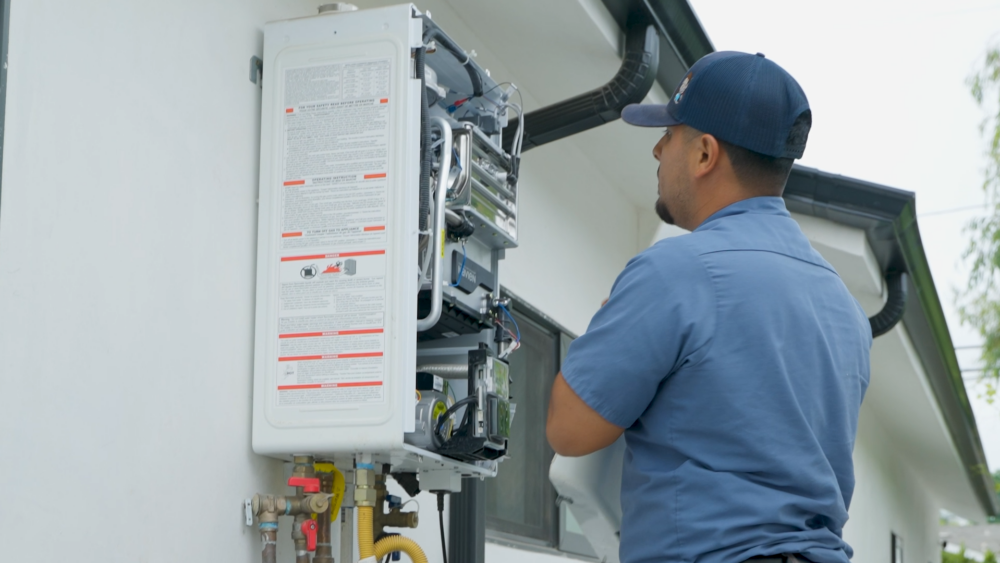 A Monkey Wrench technician is visually inspecting the inside of a tankless water heater.