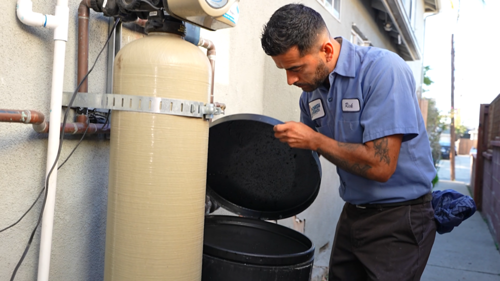 A Monkey Wrench technician is checking the salt levels of a water softener.