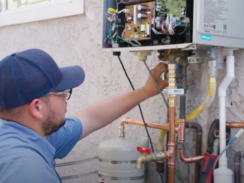 A Monkey Wrench technician inspecting the connections of a tankless water heater.