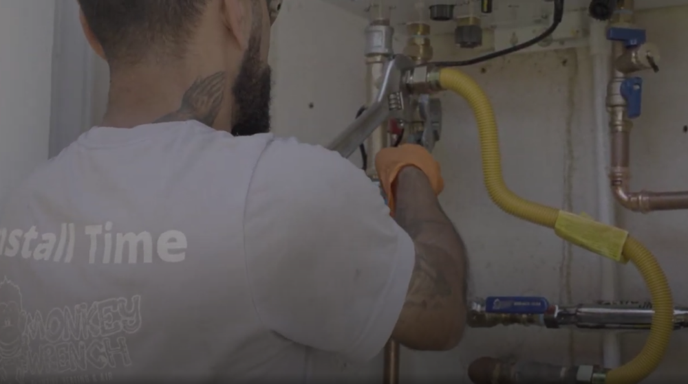 A Monkey Wrench technician performing maintenance on a Navien tankless water heater.