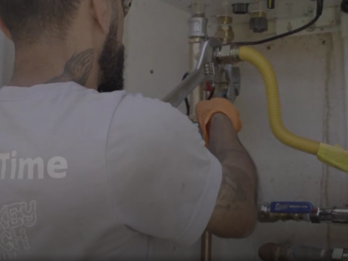 A Monkey Wrench technician performing maintenance on a Navien tankless water heater.