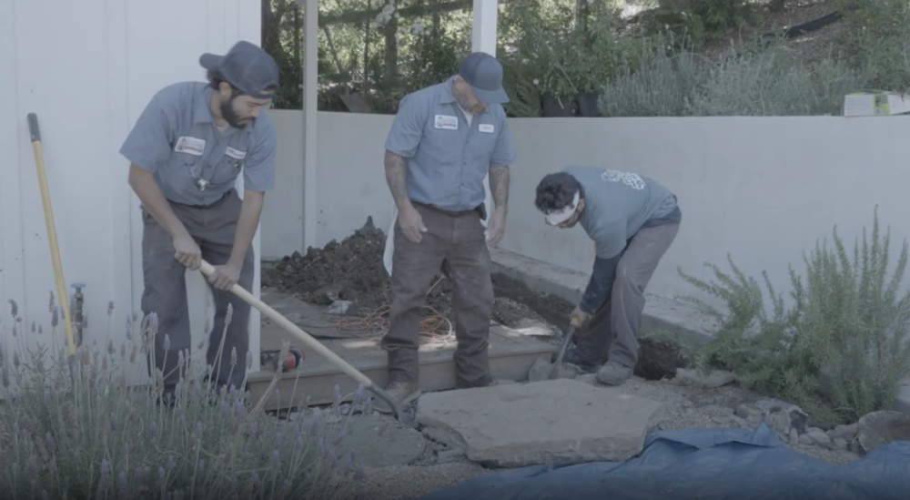 A trio of Monkey Wrench technicians are digging a home's yard to reach the pipes.