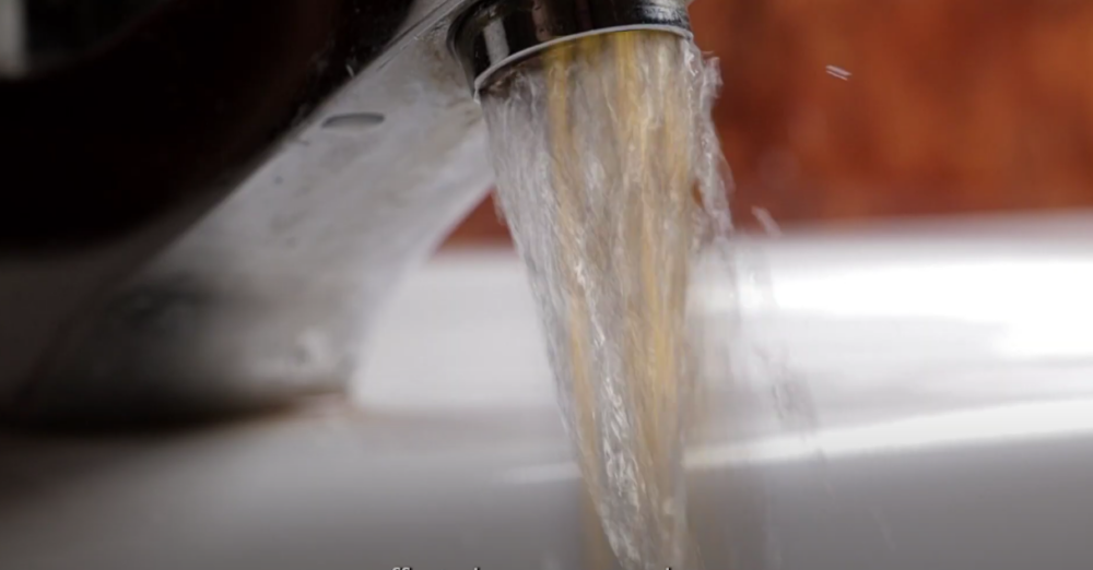 The image shows water running down a faucet.