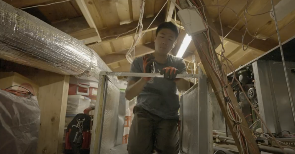 The image shows a Monkey Wrench technician using pliers on a piece of metal from an HVAC system. 