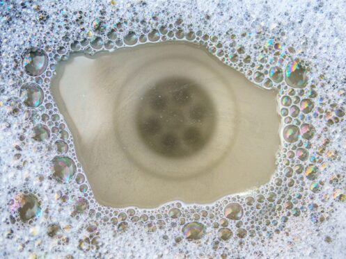 Clogged kitchen sink filled with dirty soapy water