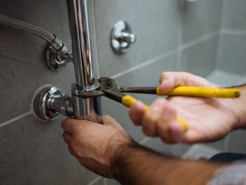 Close-up of a plumber servicing an under-sink pipe